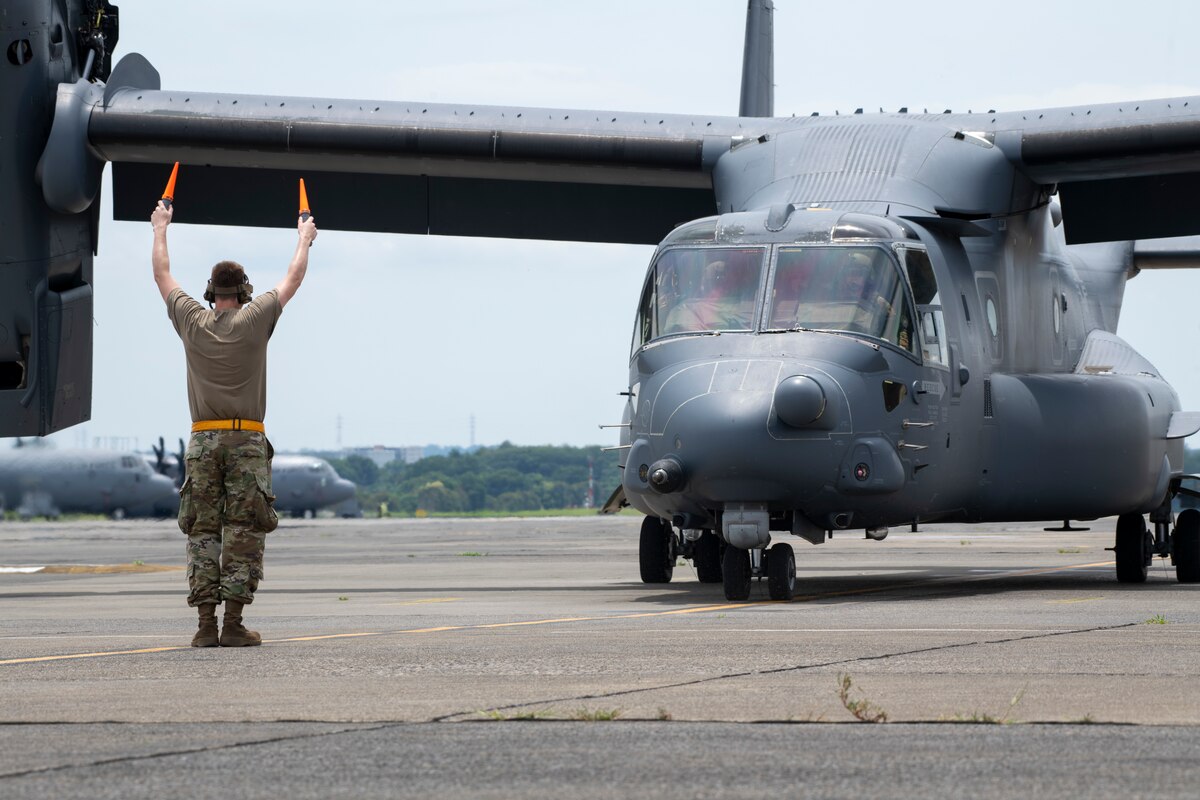 A crew chief marshals a CV-22B Osprey.