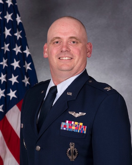 Man in military uniform in front of a flag