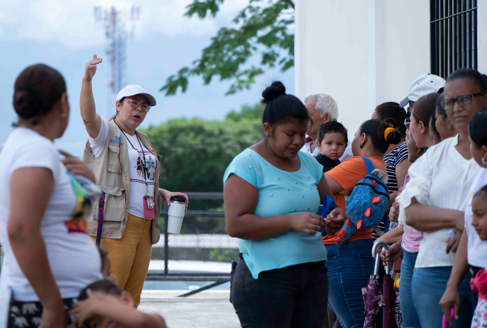 A photo of a woman pointing towards the venue to a group of patients waiting in line.