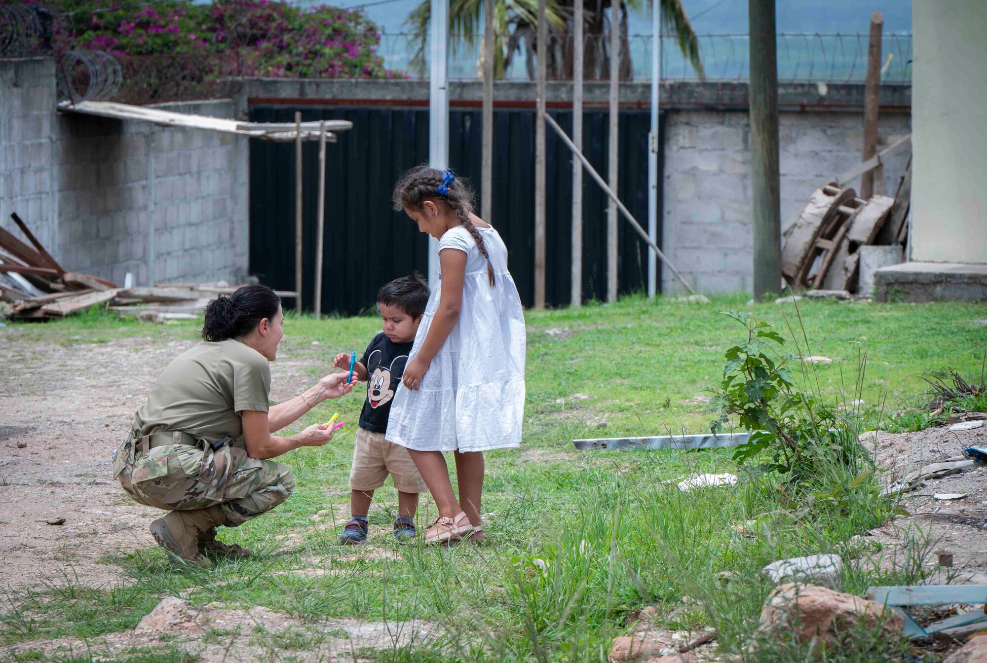 A photo of a military member bending down giving bubbles to children.
