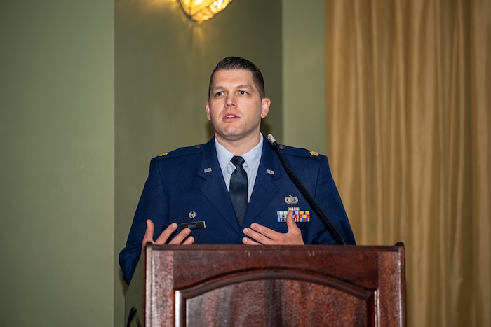 Maj. Moore gestures with his hands while giving a speech behind a podium