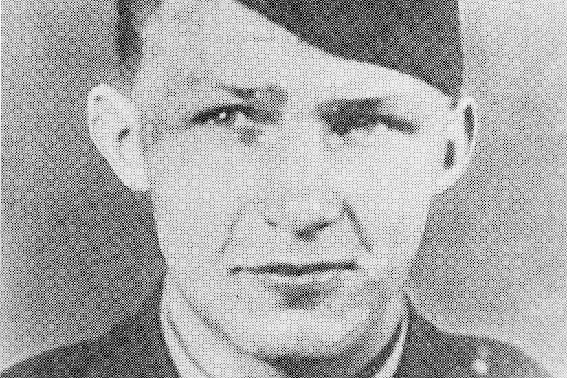 A man in uniform and cap poses for a photo.