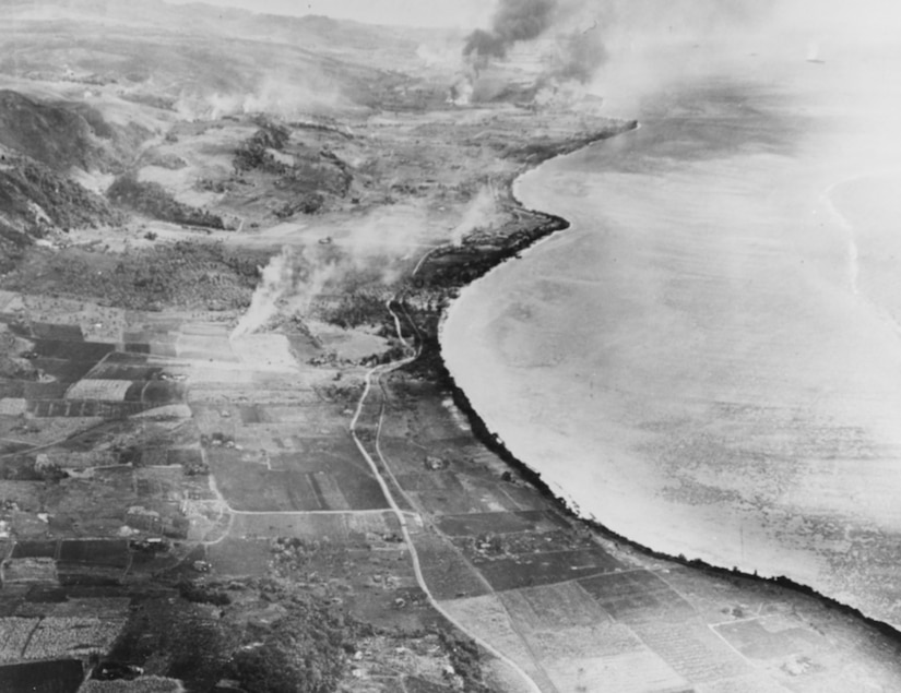 Clusters of smoke rise from areas of land along a coastline.