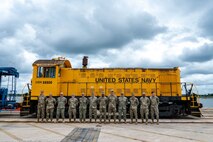 Military personal stand in front of a train