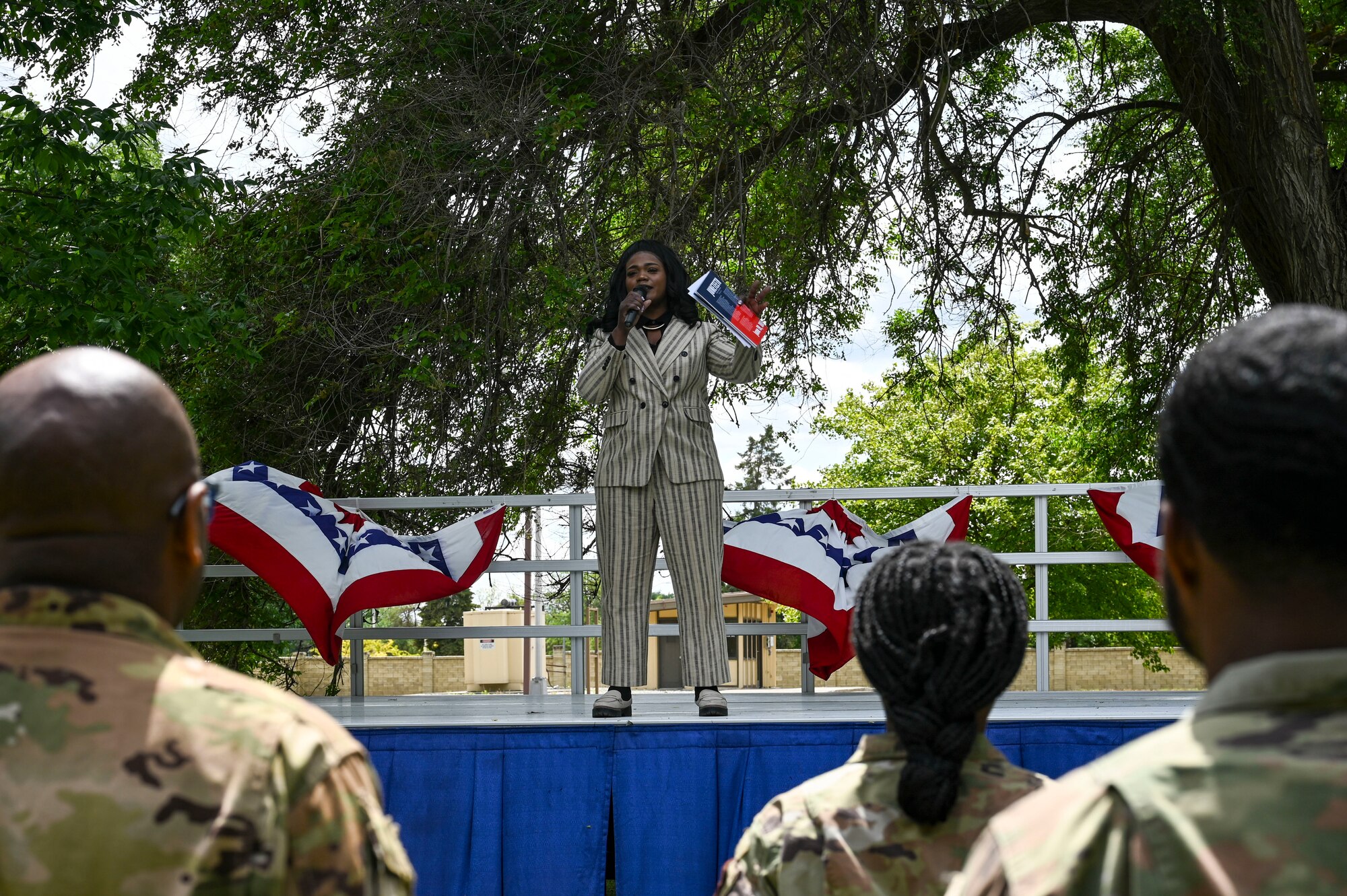 A woman speaks on a stage to an audience.