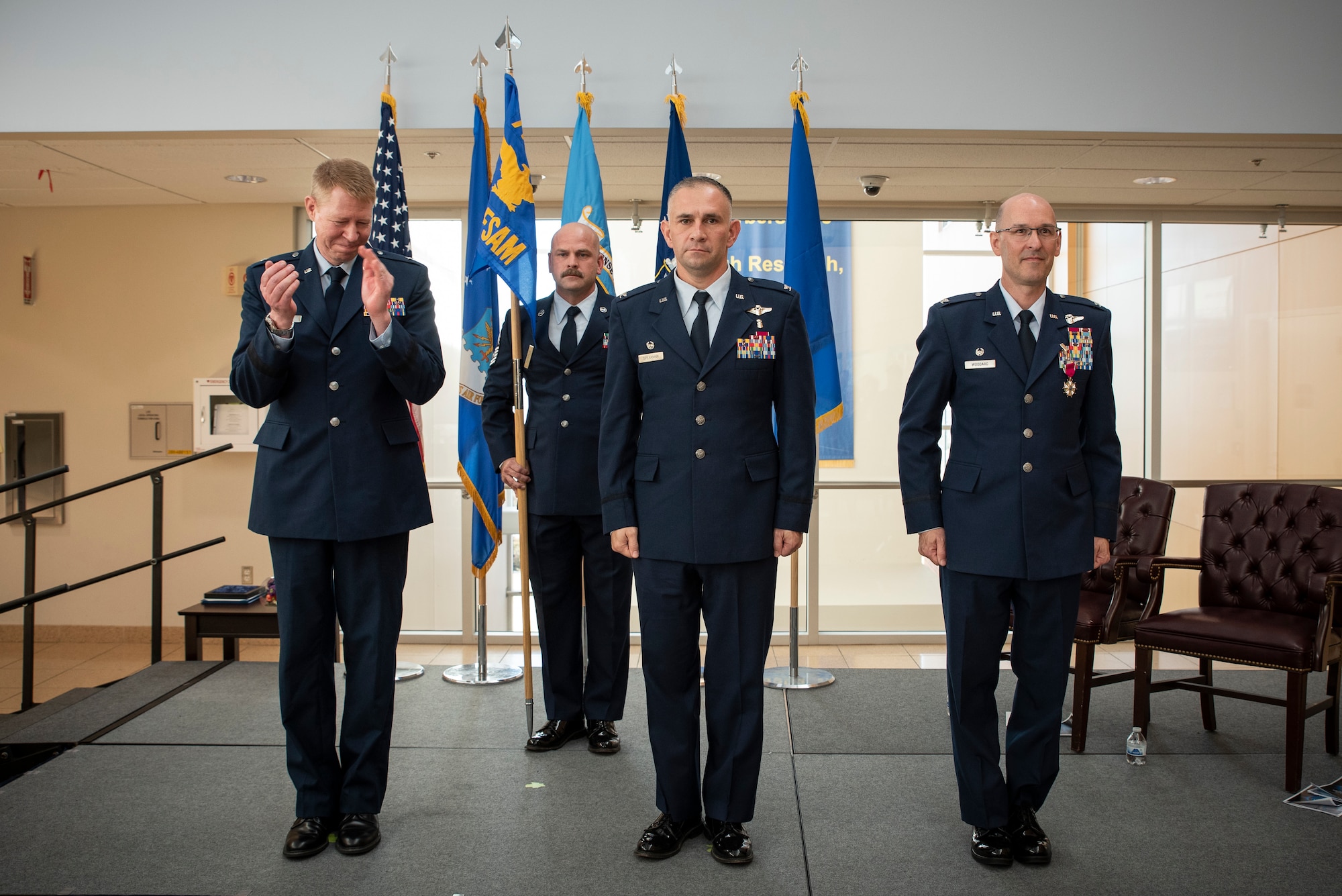 711th Human Performance Wing Commander Brig. Gen. (Dr.) Robert K. Bogart, far left, applauds as Col. (Dr.) Richard O. Speakman, middle, is formally announced as the Commander of the United States School of Aerospace Medicine, or USAFSAM, at a Change of Command ceremony at Wright-Patterson Air Force Base, Ohio, July 3, 2024, while outgoing USAFSAM Commander Col. (Dr.) Tory Woodard, right, stands alongside Speakman to signify his relinquishment of duty as USAFSAM Commander. “You are taking over an incredible organization filled with extraordinary talents and dedication across the range of military, civilian and support personnel,” Woodard said to Speakman at the ceremony. “You're the perfect person to take this position; I know you’ll do well.” (U.S. Air Force photo / Rick Eldridge)