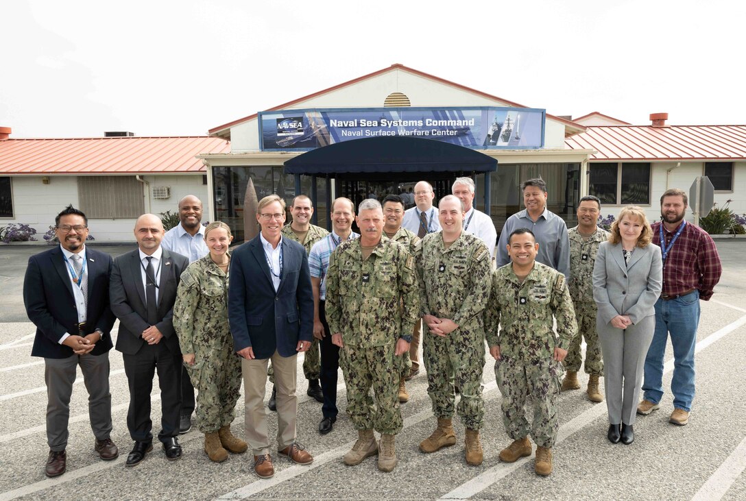 Dr. Peter Adair (center left), technical director of NSWC Panama City Division, poses for a group photo with NSWC Port Hueneme Division (PHD) Commanding Officer Capt. Tony Holmes (center) and other command and department leaders prior to a briefing, May 2. It was Adair’s last day of his swap with NSWC PHD Technical Director Jeff Koe, who spent the week in Panama City. (U.S. Navy photo by Dana Rene White/Released)