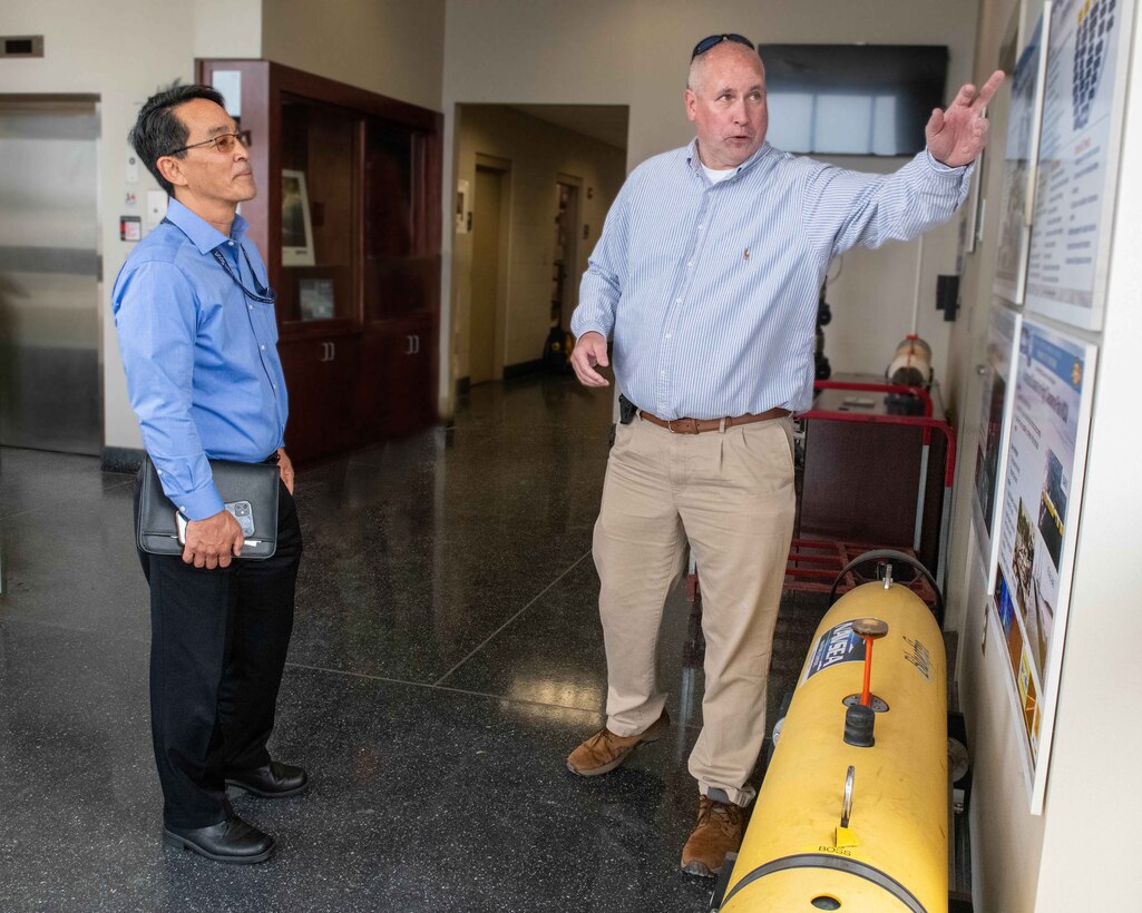 (right) Dan Kucik, NSWC PCD Unmanned Systems distinguished engineer, provides Mr. Jeffrey Koe with an overview of this Navy lab’s more than 60-year history in developing and fielding unmanned systems at NSWC PCD’s Littoral Warfare Research Complex, April 30. (U.S. Navy photo by Eddie Green)