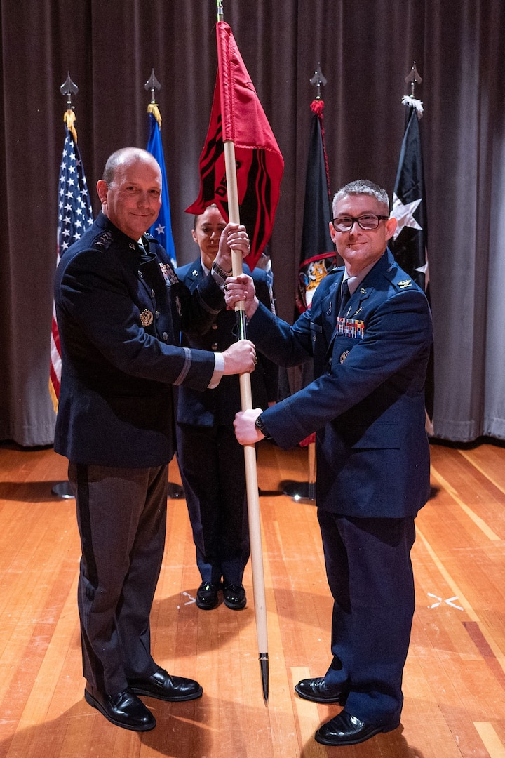 Two men hold a flag during a ceremony.