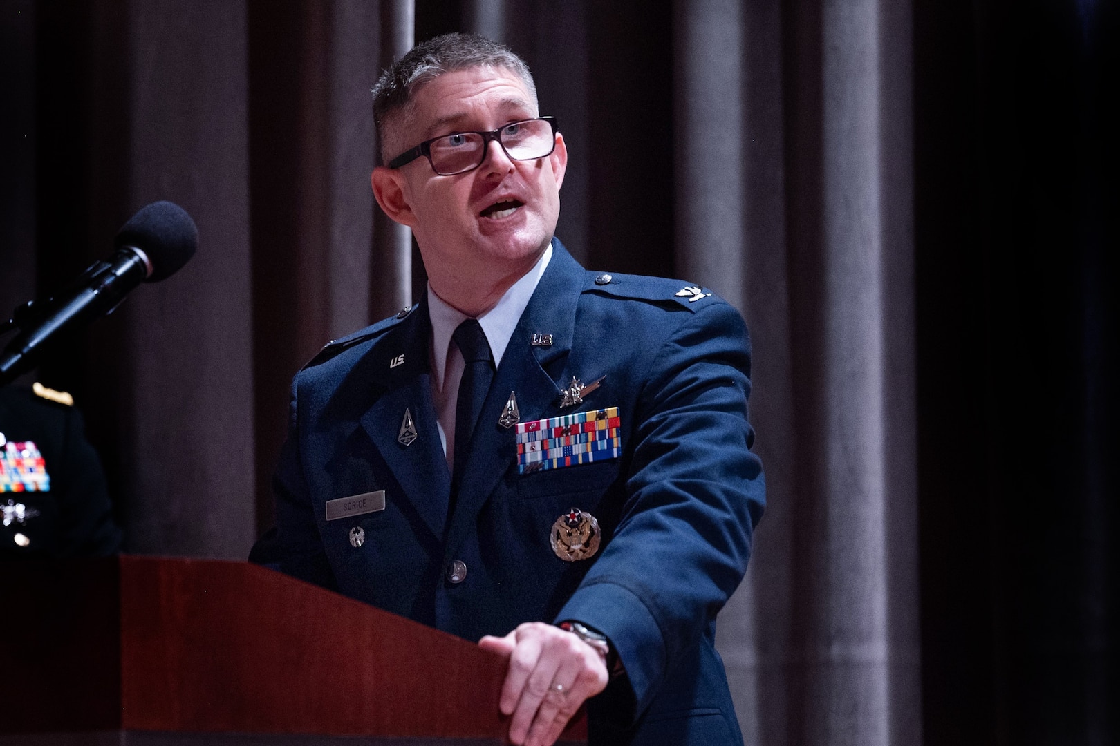 A man speaks into a microphone at a podium.