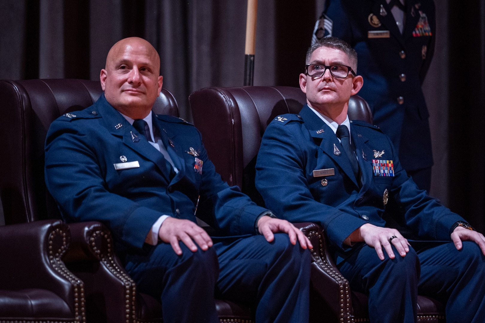 Two men in uniform sit in chairs.