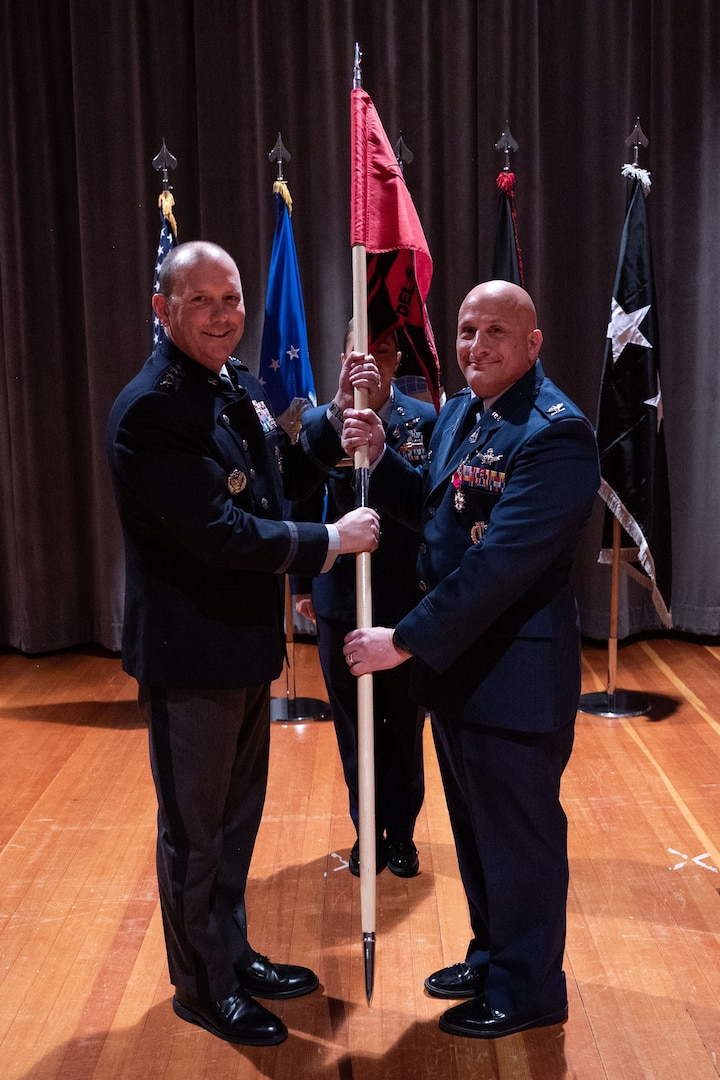 Two men in uniform hold a flag together.