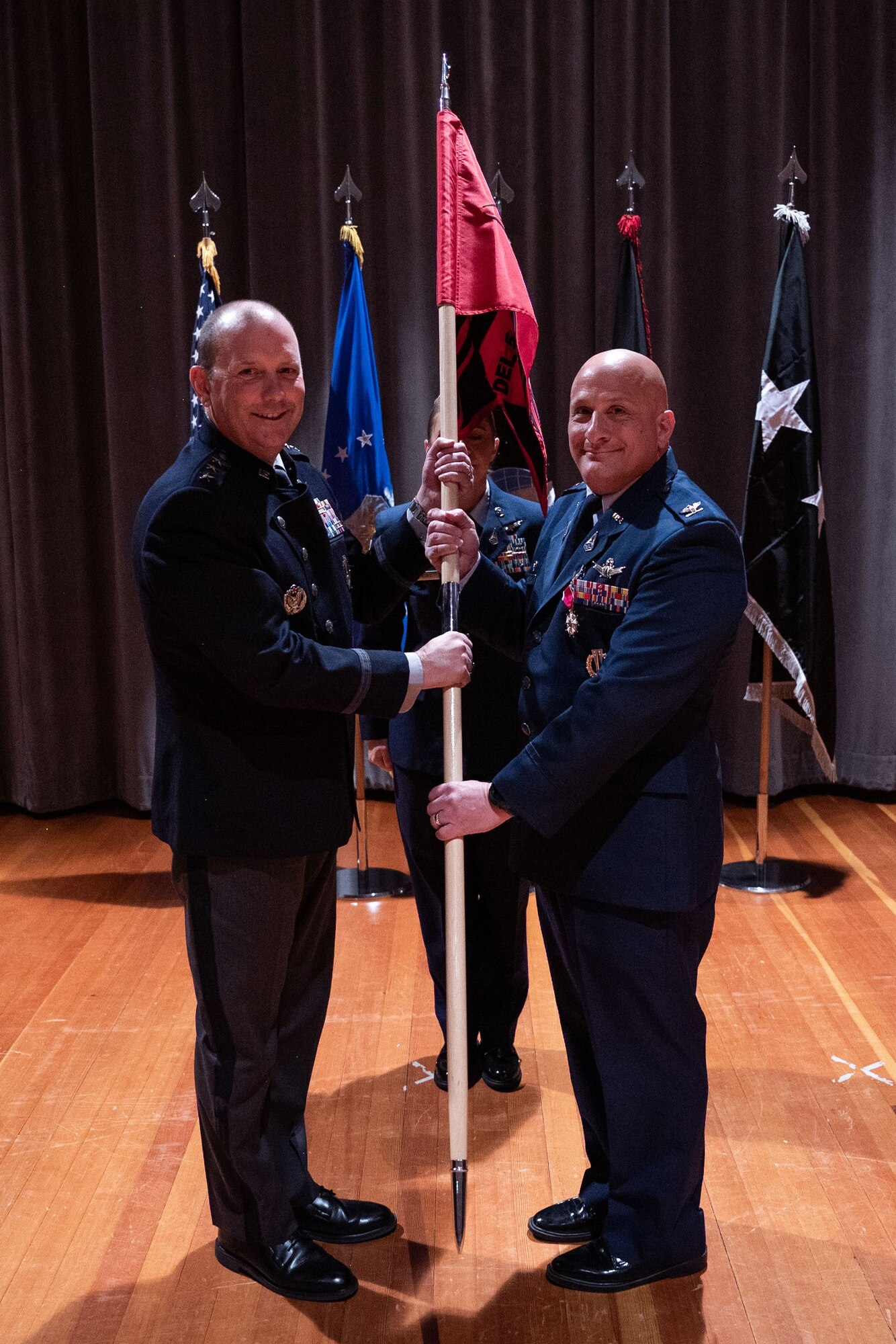 Two men in uniform hold a flag together.