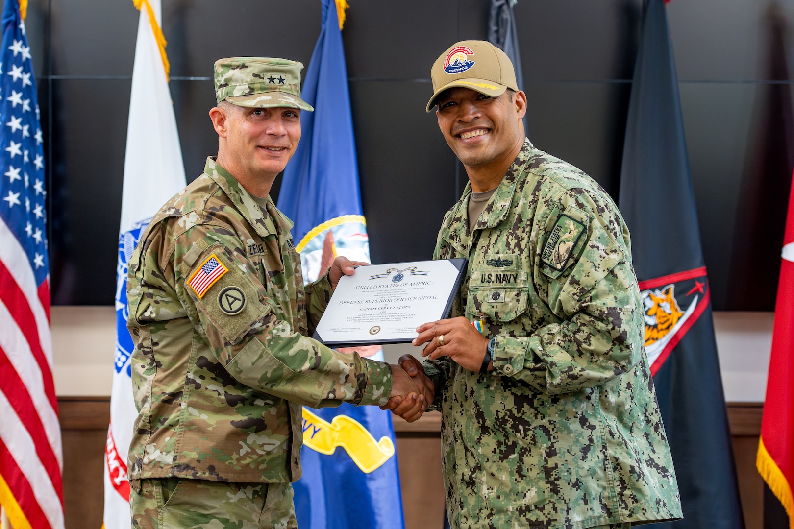 Two military members pose for a photo holding a certificate