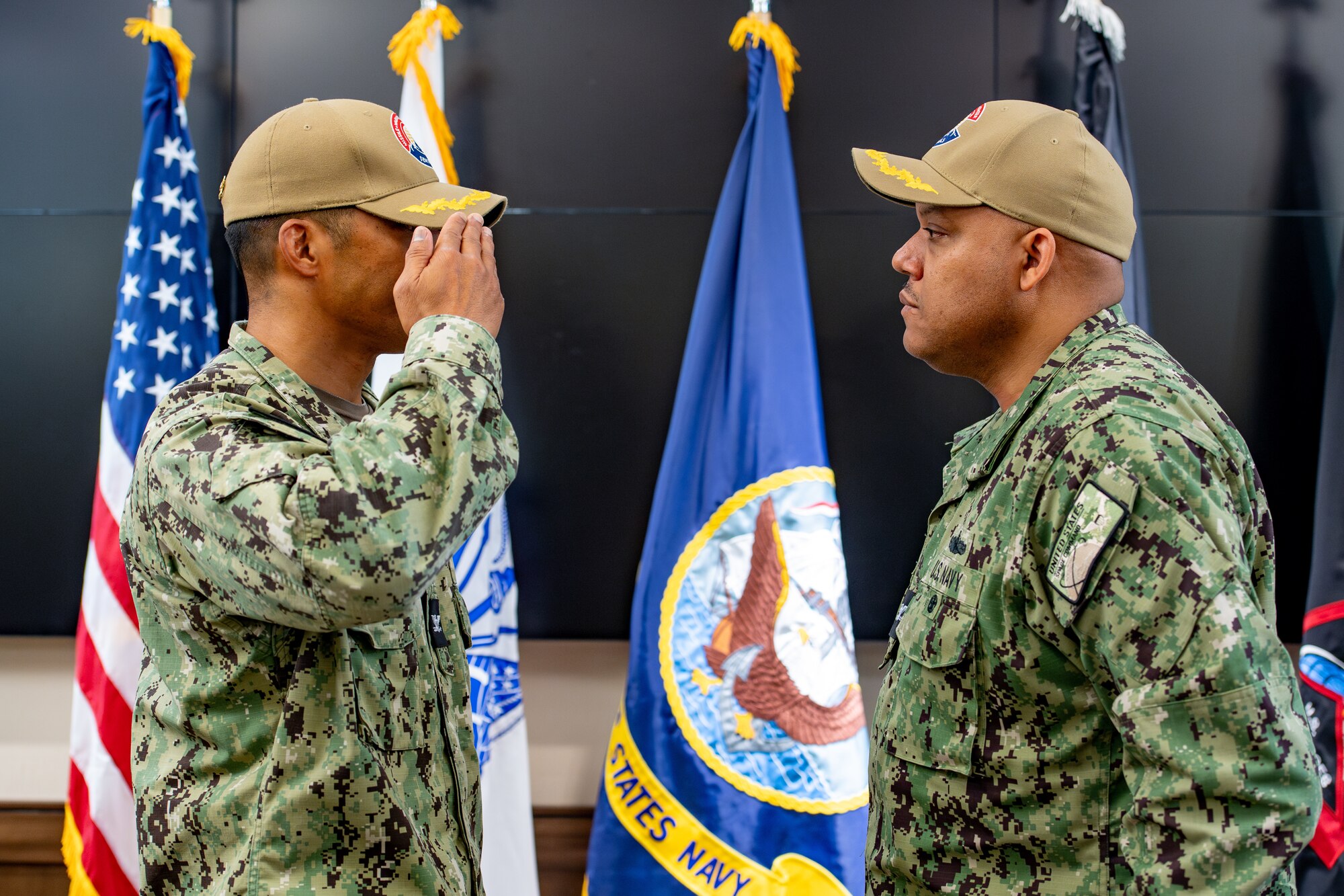One man in Navy uniform saluting another man in Navy uniform