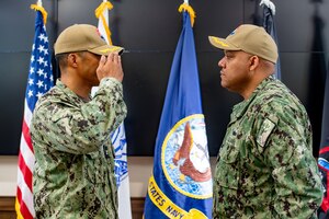 One man in Navy uniform saluting another man in Navy uniform