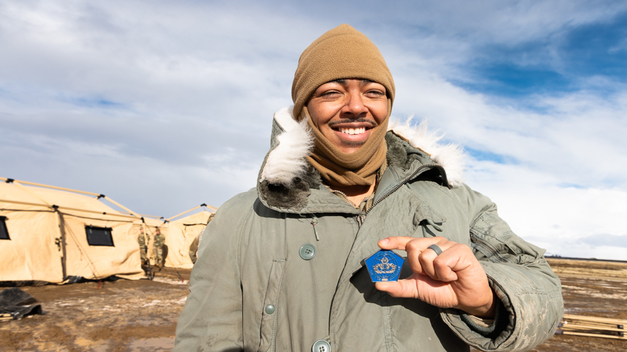 An Airman holds a coin in his hand outside