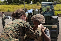 U.S. Marine Corps Capt. Stephanie Davis, a communication strategy and operations officer with I Marine Expeditionary Force (Forward) helps a child try on a Kevlar helmet during a military equipment exposition as part of exercise Valiant Shield 24 at Palau International Airport, Airai, Palau.