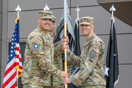  Uniformed members hold a guidon during the change of command of space Delta 9.