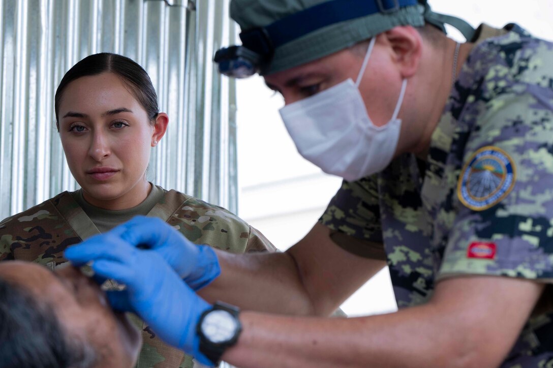 A photo of a military member watching another extract teeth.
