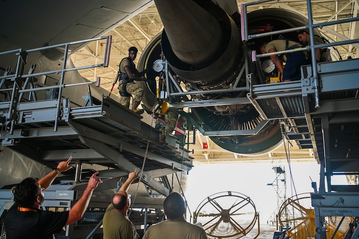 Justin Nagle, 433rd Maintenance Group Air Force Engineering and Technical Services advisor, and Senior Master Sgt. Sean Preston, 433rd Maintenance Squadron propulsion flight chief, give instructions to Senior Airman Evan Sherman, a 433rd Aircraft Maintenance Squadron aerospace propulsion technician, as he and a team of 433rd MXG maintainers lower a General Electric F-138 jet engine from a C-5M Super Galaxy at Joint Base San Antonio-Lackland, Texas June 28, 2024.