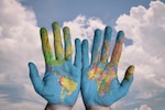 Two hands covered in world map on sky background