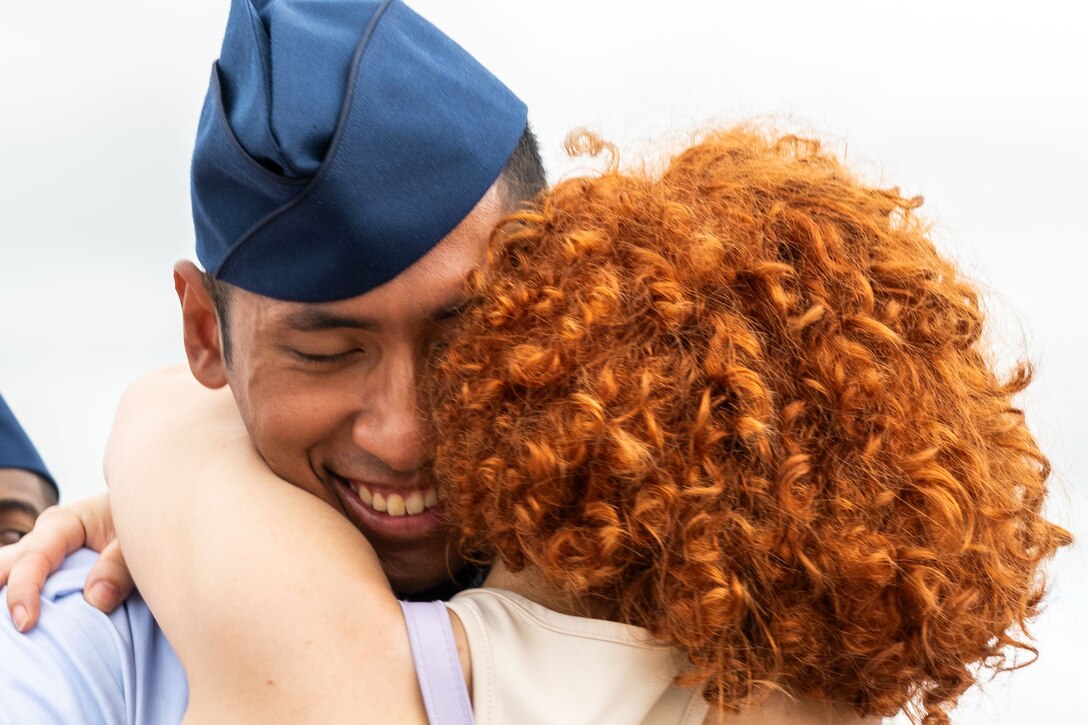 A close-up of an airman hugging a loved one with curly, red hair.