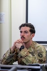 An Army Soldier wearing an Army camouflage uniform is gazing forward during a briefing.