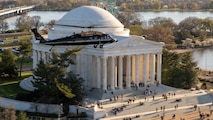 An Army VH-60M "gold top" Black Hawk helicopter flies over the Potomac near the Jefferson Memorial.