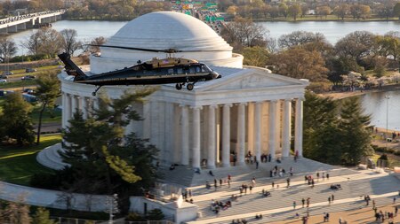 An Army VH-60M "gold top" Black Hawk helicopter flies over the Potomac near the Jefferson Memorial.