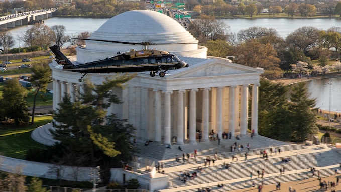 An Army VH-60M "gold top" Black Hawk helicopter flies over the Potomac near the Jefferson Memorial.