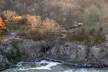 An Army VH-60M "gold top" Black Hawk helicopter flies over rock formations near Great Falls, Md.