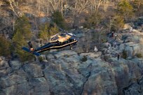 An Army VH-60M "gold top" Black Hawk helicopter flies over rock formations near Great Falls, Maryland.