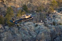 An Army VH-60M "gold top" Black Hawk helicopter flies over rock formations near Great Falls, Maryland.