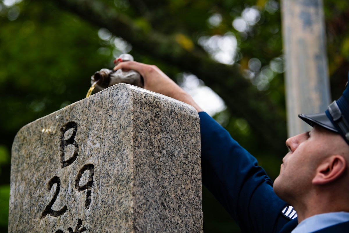 An Airman pours bourbon over a memorial.
