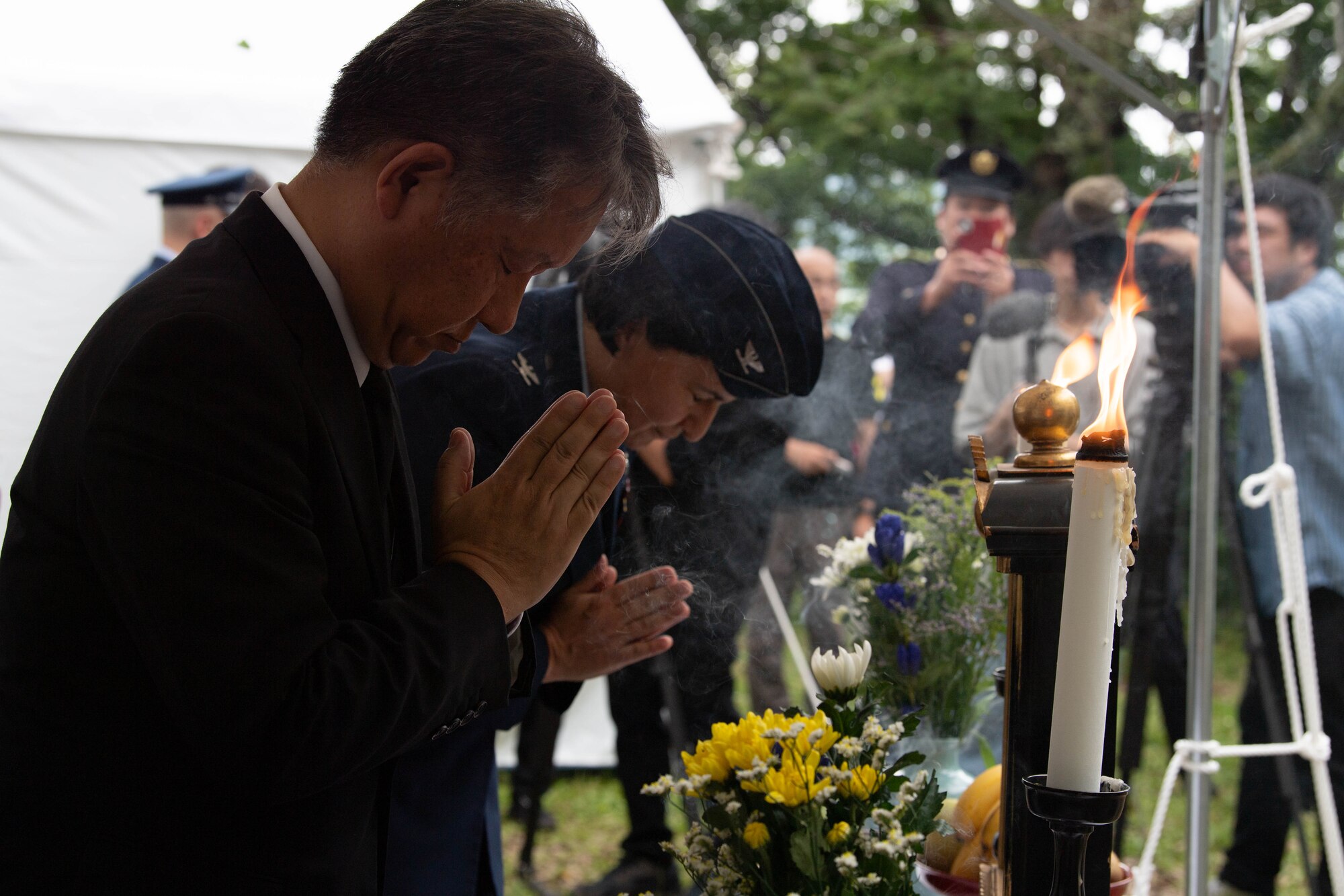 Two people pray before an incense offering.