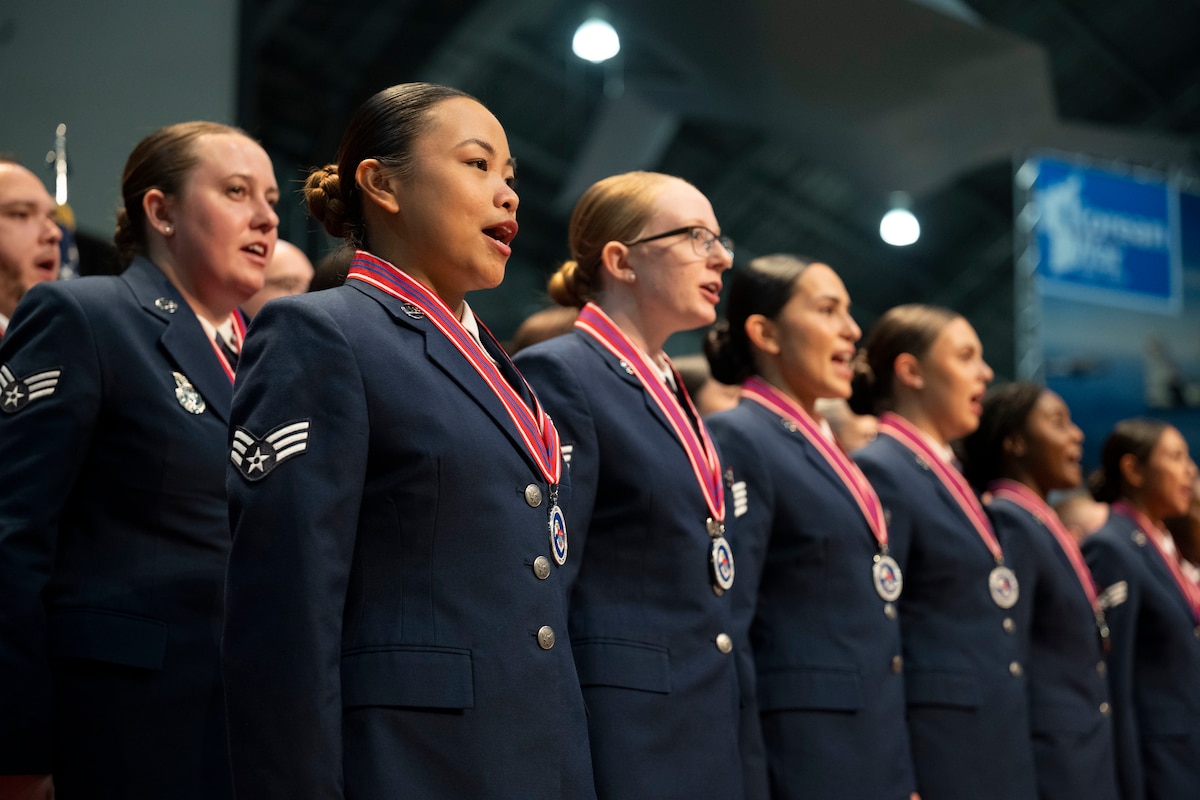 A group of uniformed service members are pictured standing on stage during a graduation ceremony.