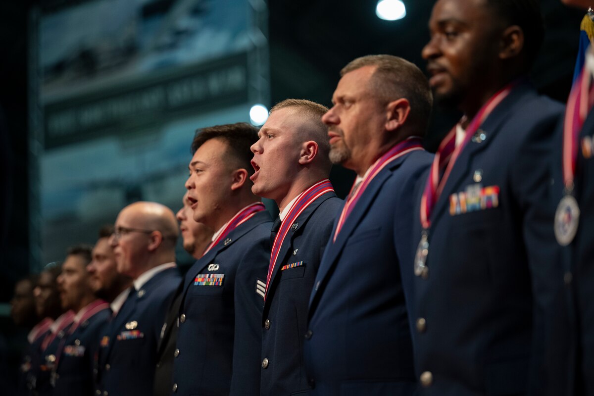 A group of uniformed service members stand in a line during a graduation ceremony.