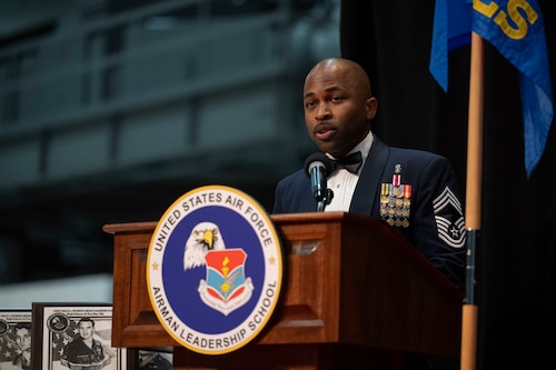 A man wearing a uniform stands behind a podium speaking during a graduation ceremony.