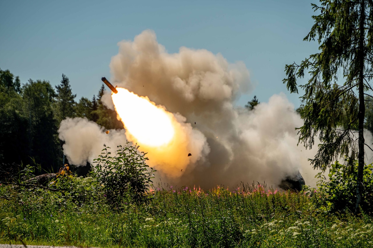 A missile fires amid trees and vegetation.