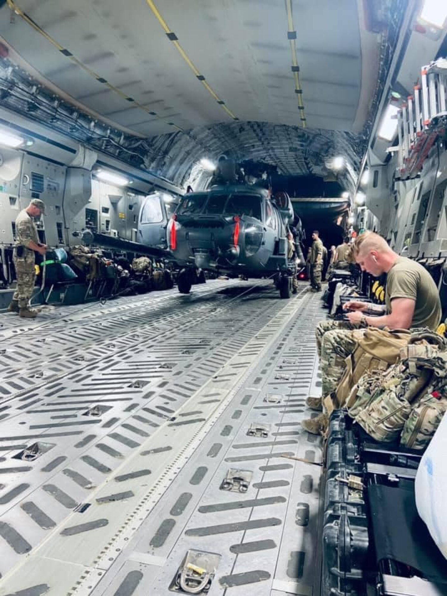 Airmen and a UH-60 Black Hawk sit aboard a C-17 Globemaster