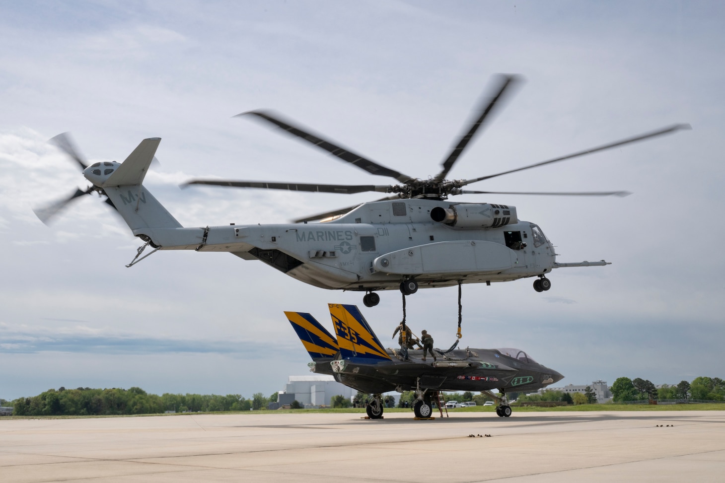 U.S. Marine Corps members of the Helicopter Support Team (HST) from Combat Logistics Battalion 26 attach a non-flying F-35C airframe from the NAS Patuxent River F-35 Integrated Test Force to a sling beneath a hovering CH-53K, operated by U.S. Marine Corps pilots from VMX-1, at NAS Patuxent River, MD, April 24, 2024.