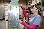Shevaun Jones, a sheet metal worker in the H-53 Aircraft Components Shop at Fleet Readiness Center East (FRCE), uses a feeler gauge to check for excessive gaps on the mount feet of an H-53 spar fitting. The gap check is one step in a new procedure developed and refined by a team of artisans and engineers at FRCE in order to improve the manner in which the aircraft’s spar fittings are evaluated for fit, resulting in a higher acceptance rate and faster turnaround times for the components.
