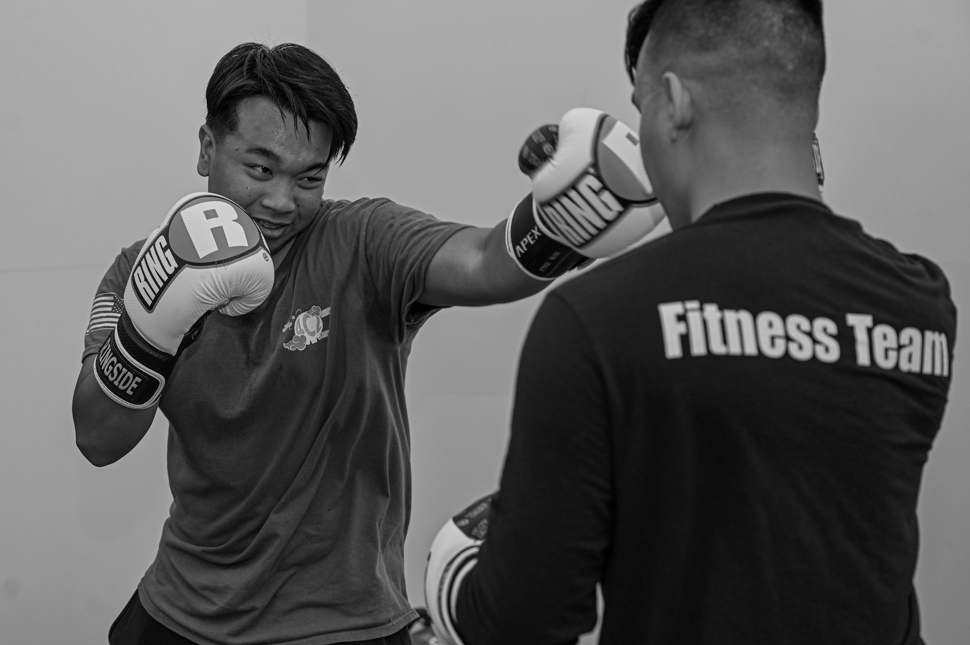 Photo of two participants practicing jabs with boxing gloves on. Photo in black and white.