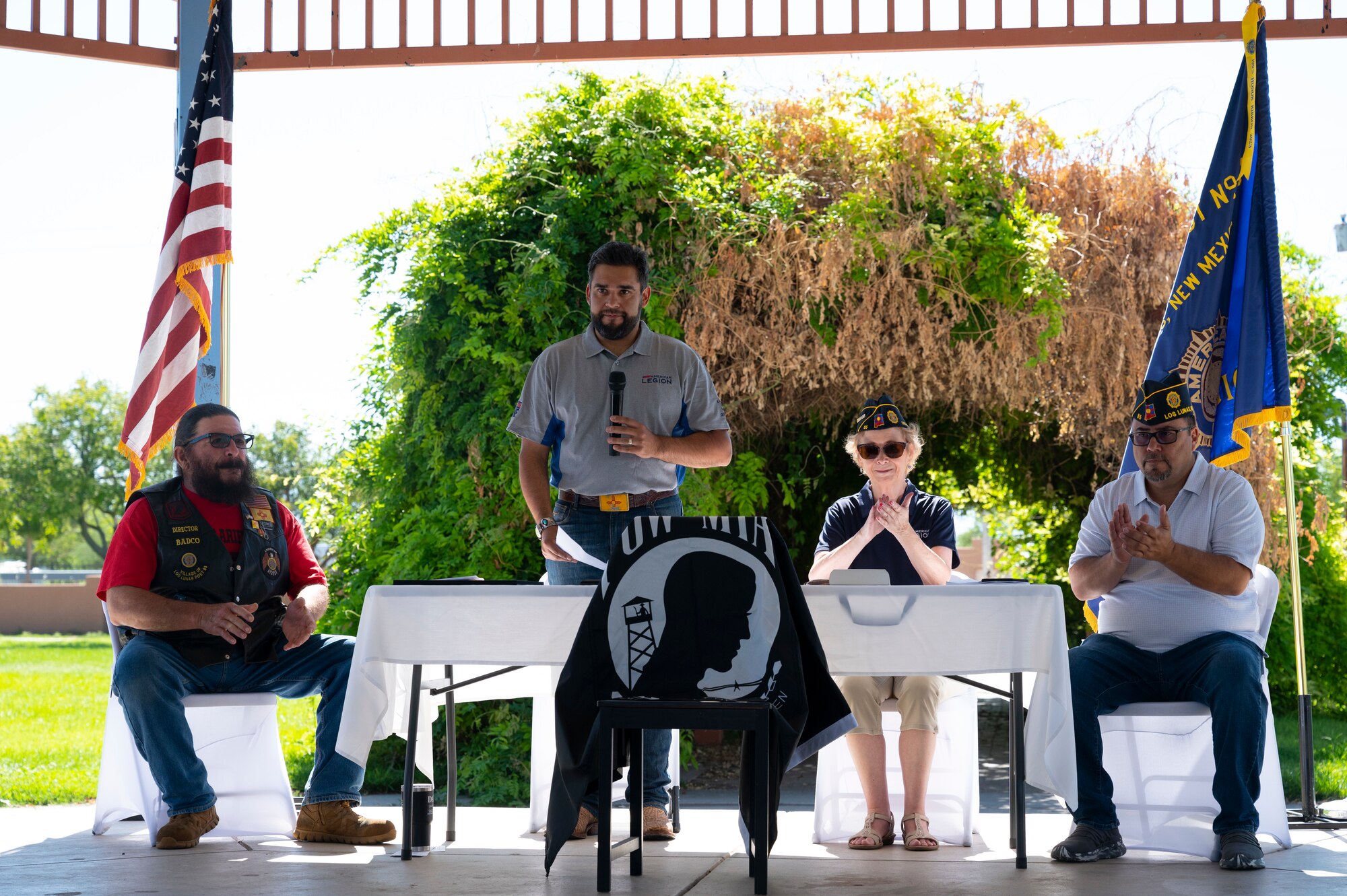 Man speaks into microphone with members sitting behind him.