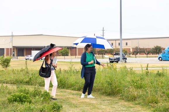 Two women walk through a prairie full of wildflowers.