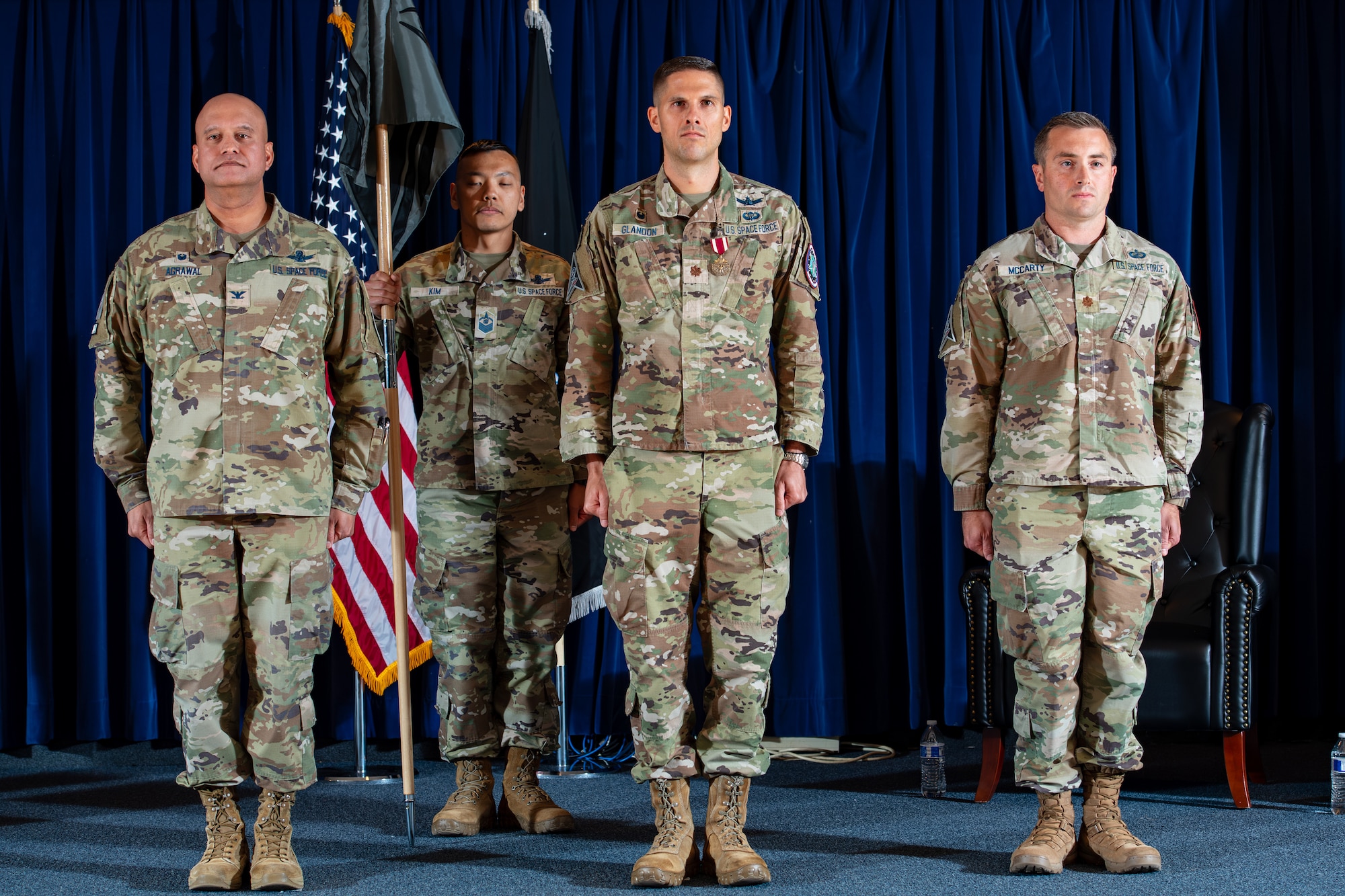 Three men in military uniforms stand at attention next to each other