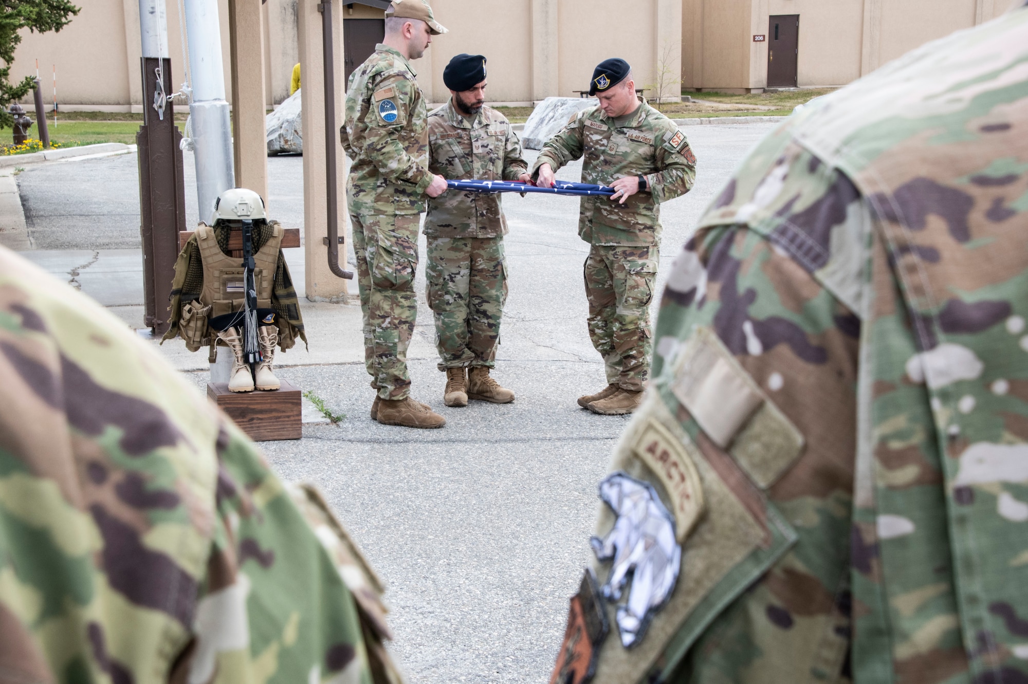 Master Sgt. Joshua Marugg, 268th Security Forces, right, Tech Sgt. Luis Maldonado, 268th Security Forces, center, and Staff Sgt. Timothy Jones, Chaplain Affairs, Maine Air National Guard, left, fold the American flag during the Final Roll ceremony held at Clear Space Force Station, Alaska, during Police Week.