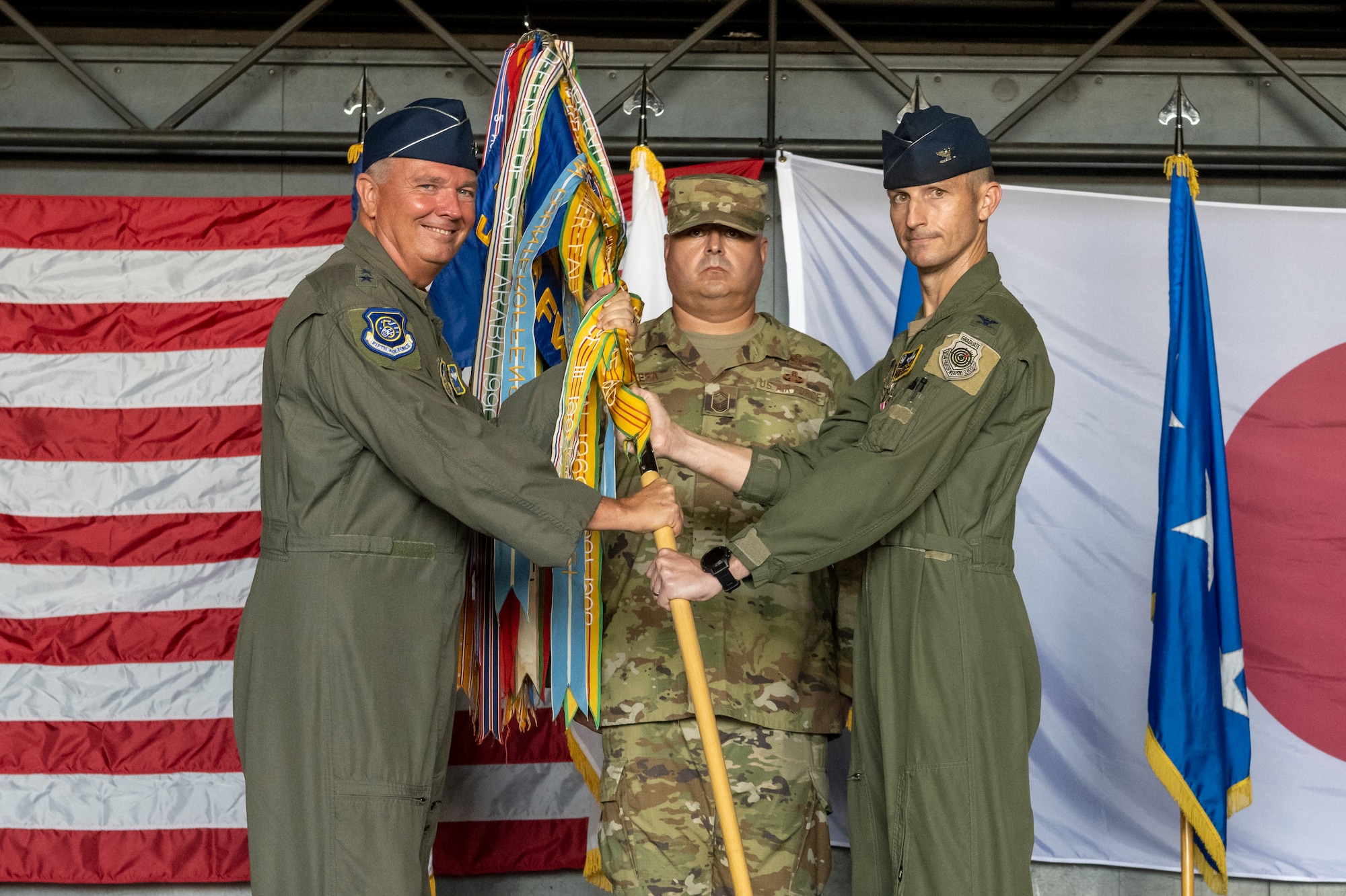 U.S. Air Force Col. Michael Richard, right, 35th Fighter Wing outgoing commander, passes a guidon to Lt. Gen. Ricky N. Rupp, left, U.S. Forces Japan and 5th Air Force commander, during the 35th FW change of command ceremony at Misawa Air Base, Japan, July 8, 2024.