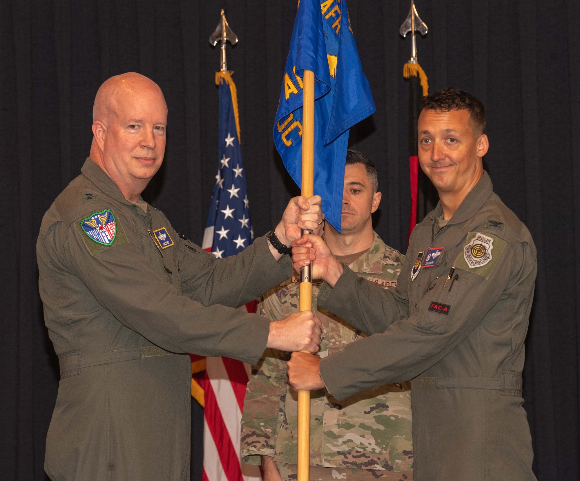 U.S. Air Force Maj. Gen. Joel Carey, U.S. Air Forces in Europe - Air Forces Africa strategic deterrence and nuclear integration director of operations, passes the unit guidon to Col. Michael McCarthy, 603rd Air Operations Center incoming commander, during a change of command ceremony at Ramstein Air Base, Germany, July 3rd, 2024.